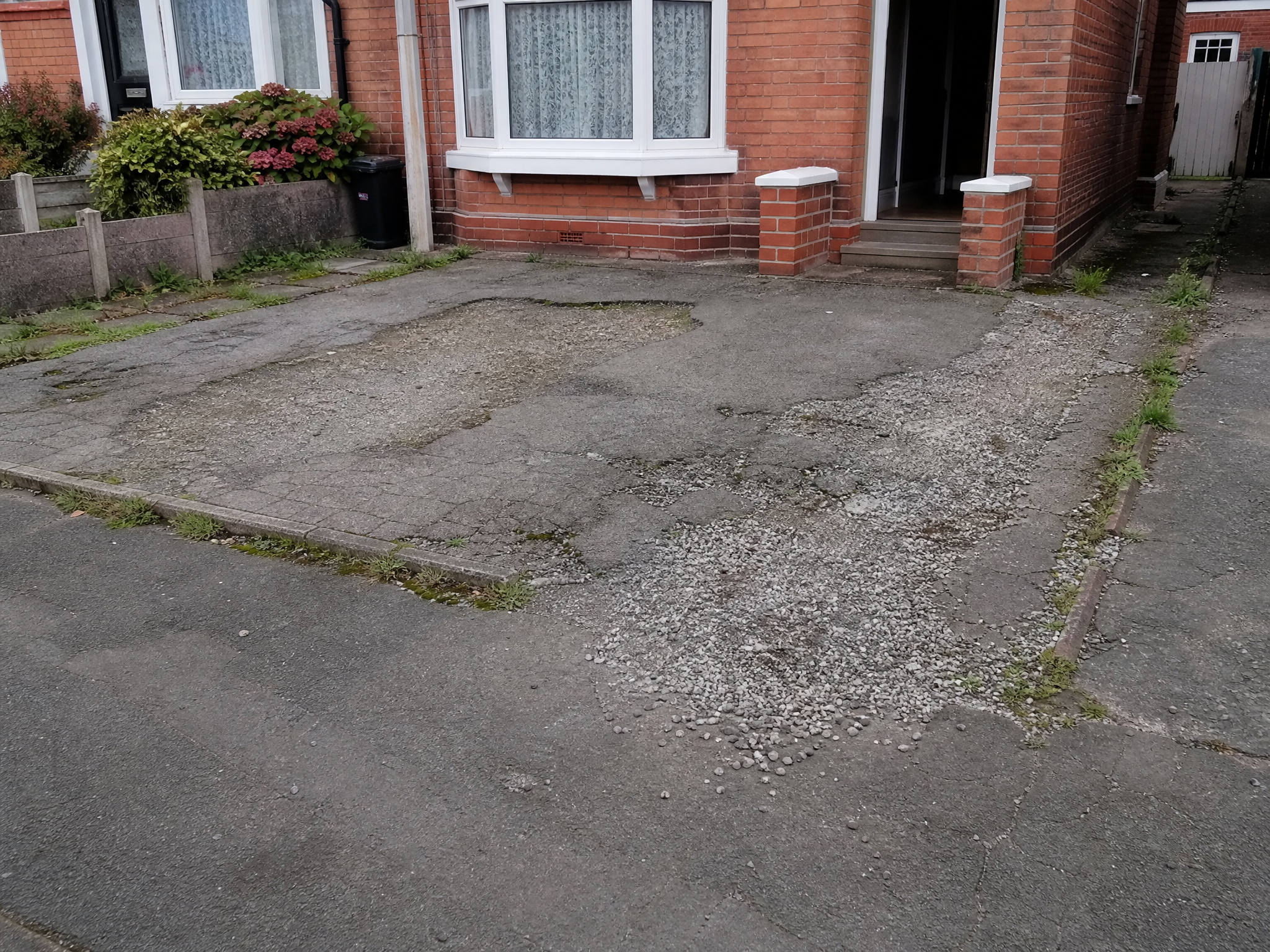 Old cracked tarmac driveway with weeds growing through, before being replaced with resin in Kettering