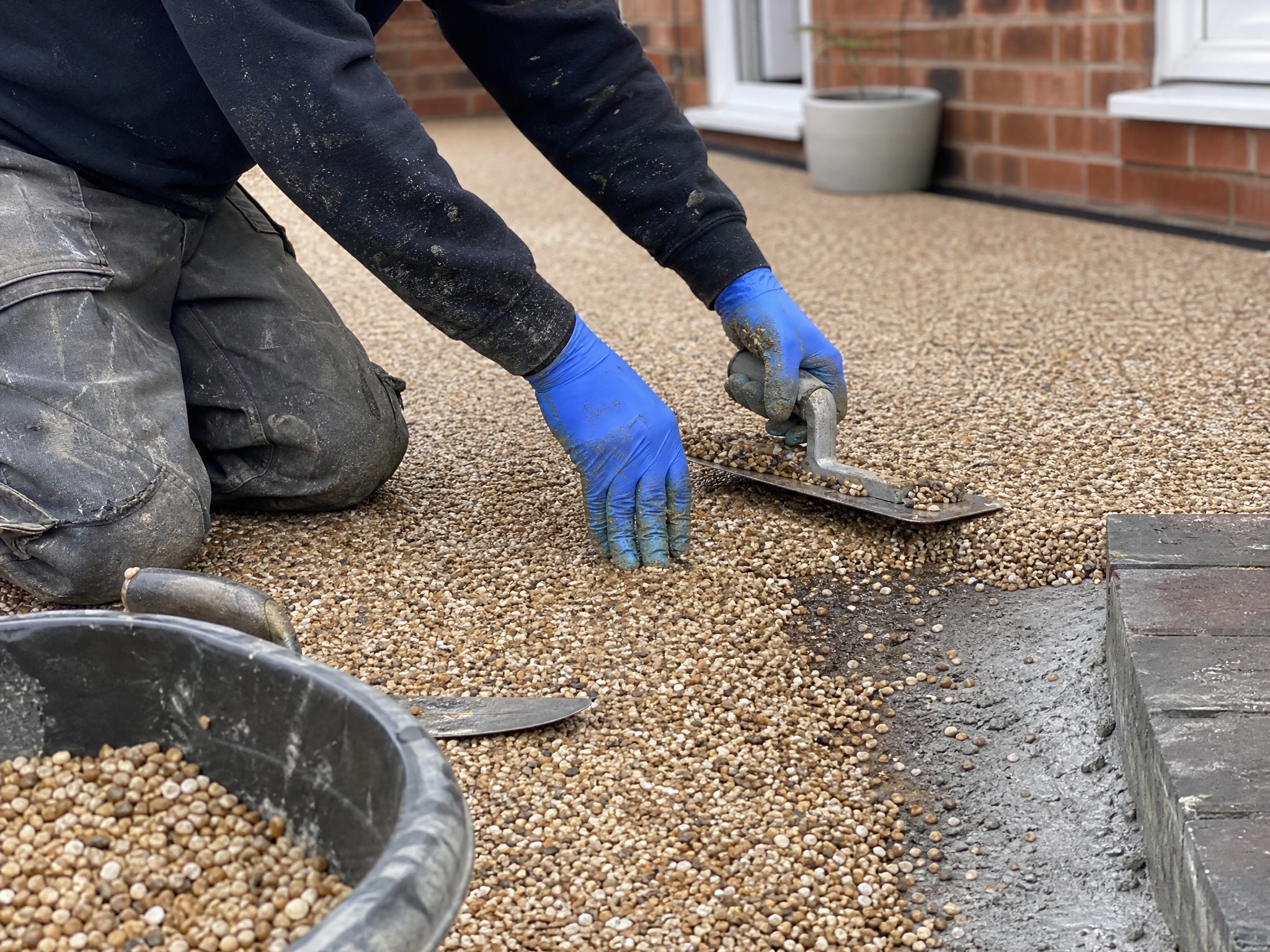 Professional installer carrying out resin driveway repairs & cleaning in a British residential property